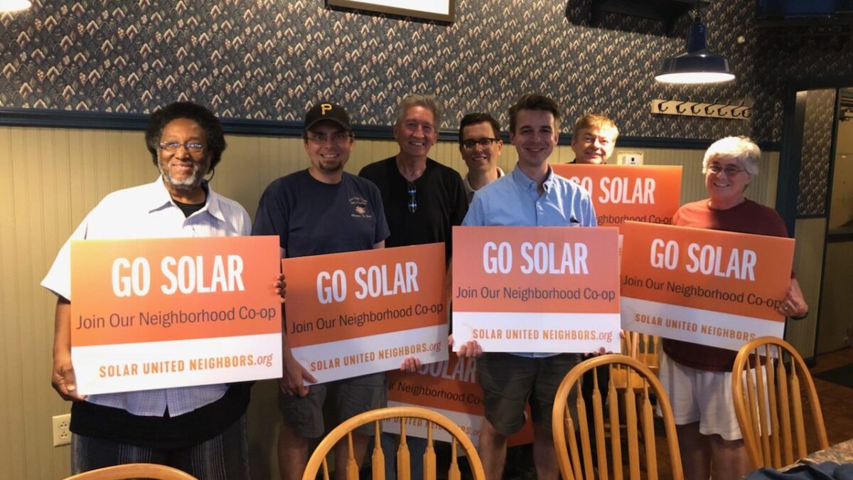 Group holding "Go solar" signs.