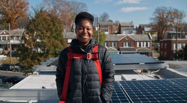 LaToya Smith, a Solar for All recipient in Ward 7, stands in front of her new solar system during the installation.