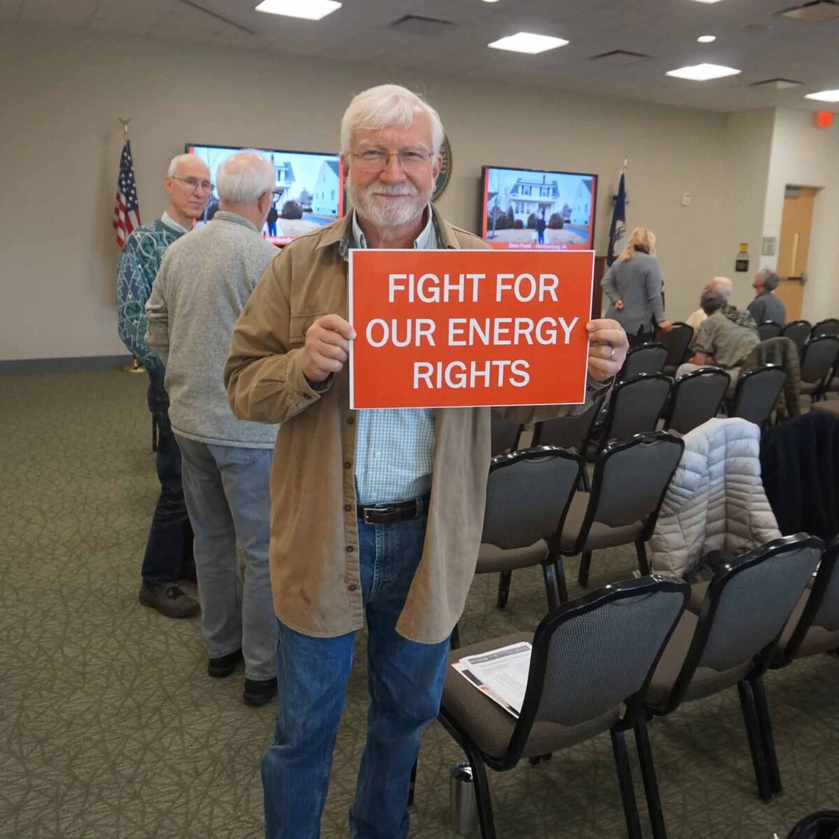 Older gentleman in glasses holding a sign that reads "Fight for our energy rights."