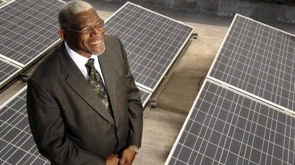 Reverend standing on a roof with solar panels looking up.