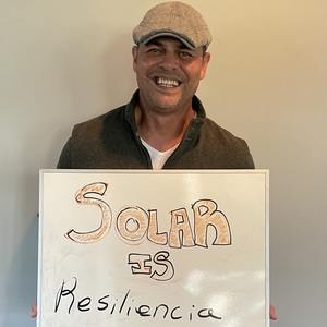 Man holding a "Solar is reslience" sign.