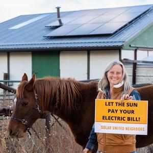 Woman standing next to horse on a farm with solar panels installed.