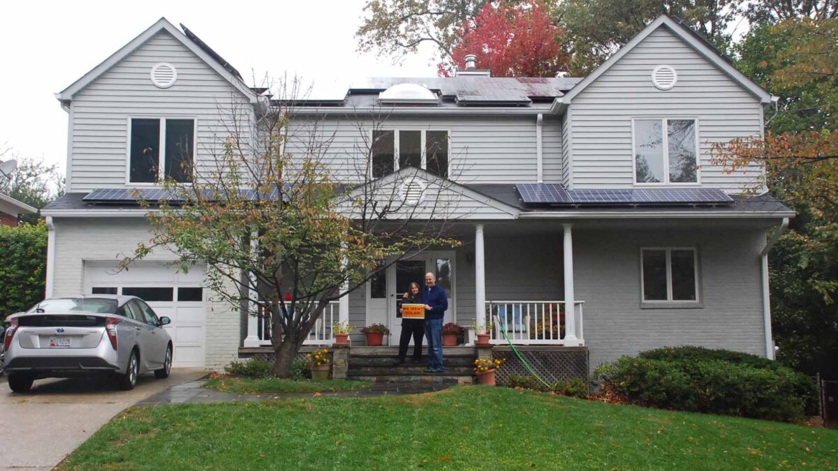 Couple standing on stairs of two-story house.