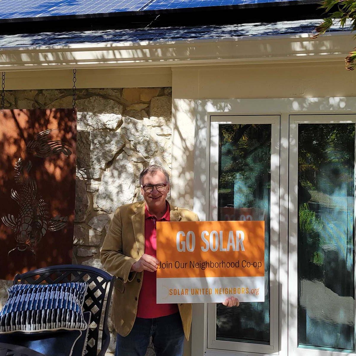 Older gentleman holding sign that reads "Go solar"