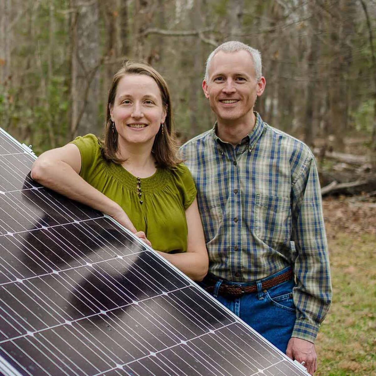 Man and woman leaning on solar panels.
