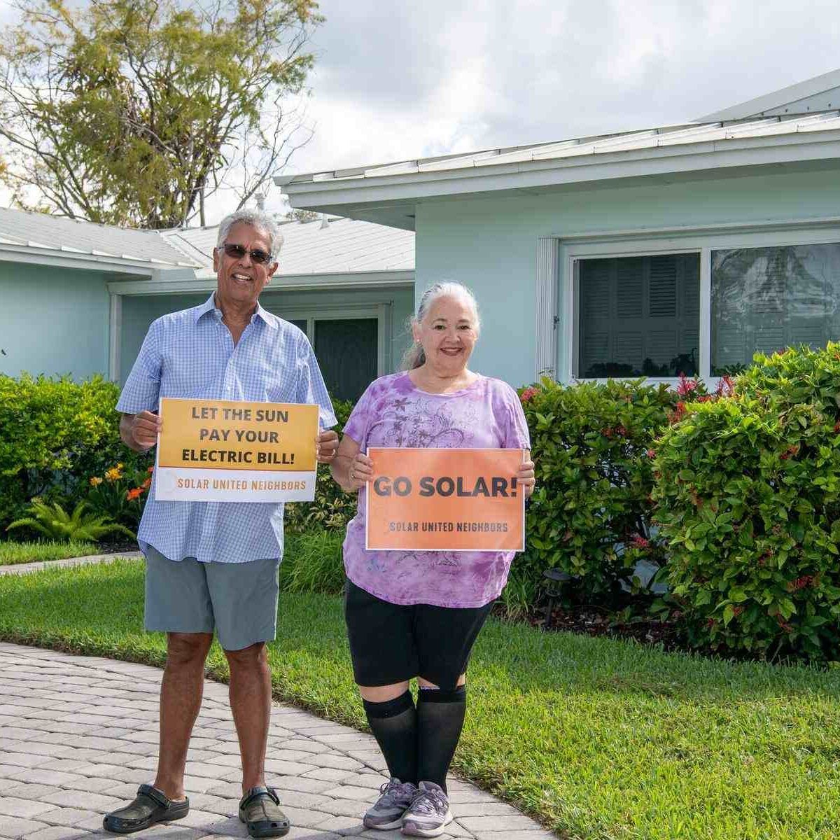 Two people standing in their front yard smiling.