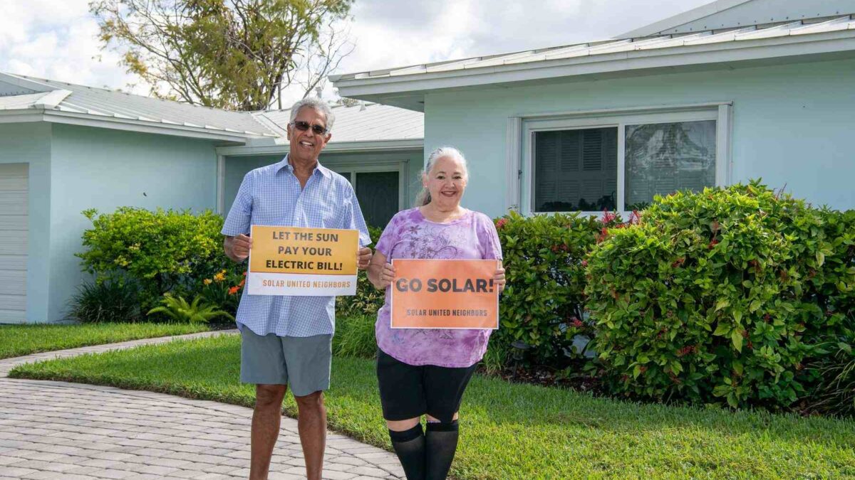 Two people standing in their front yard smiling.