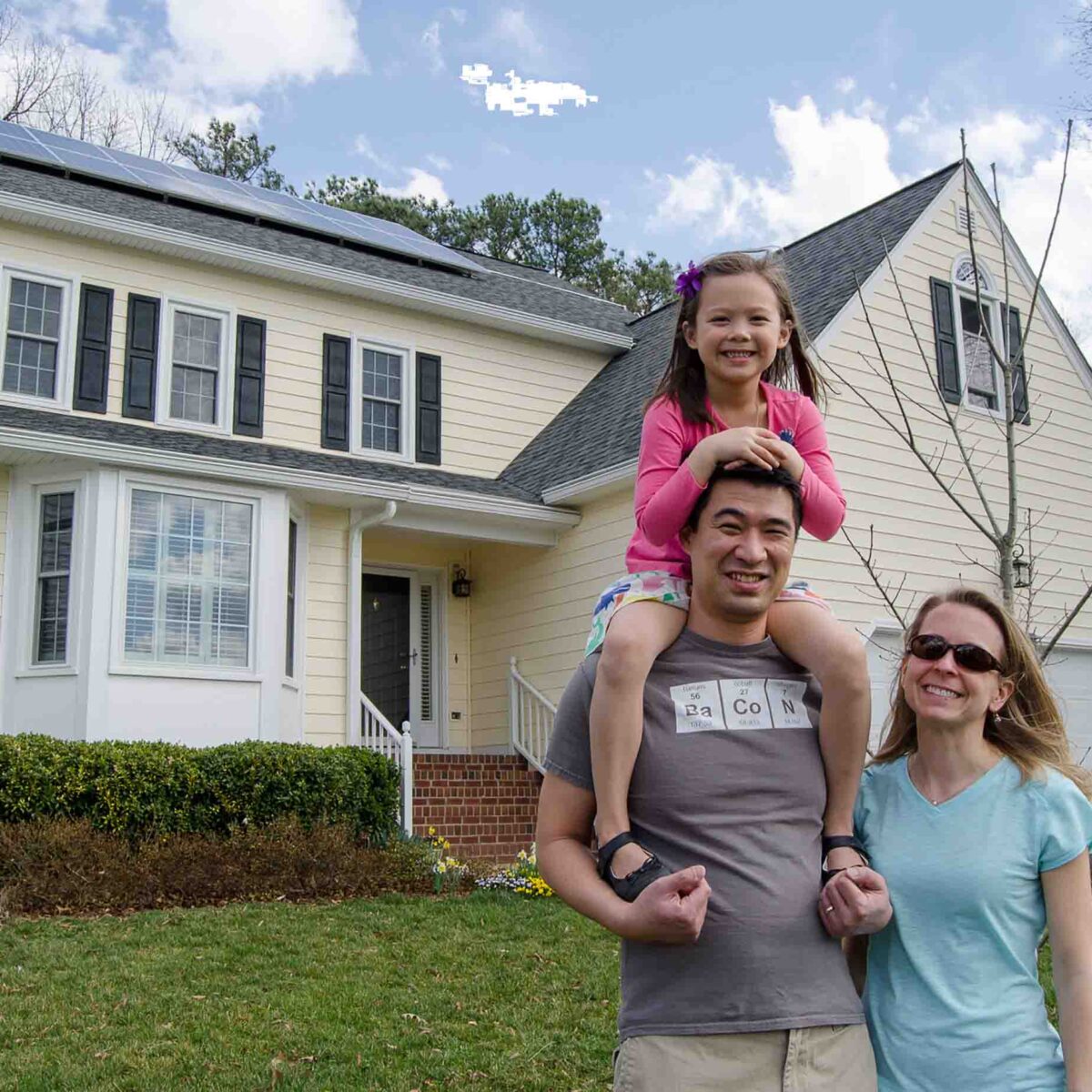 Family smiling in front of their house.