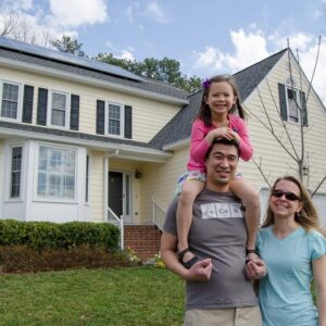 Family smiling in front of their house.