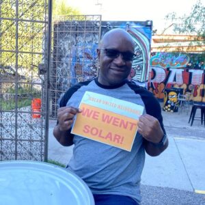 Man holding sign that says "We went solar!"