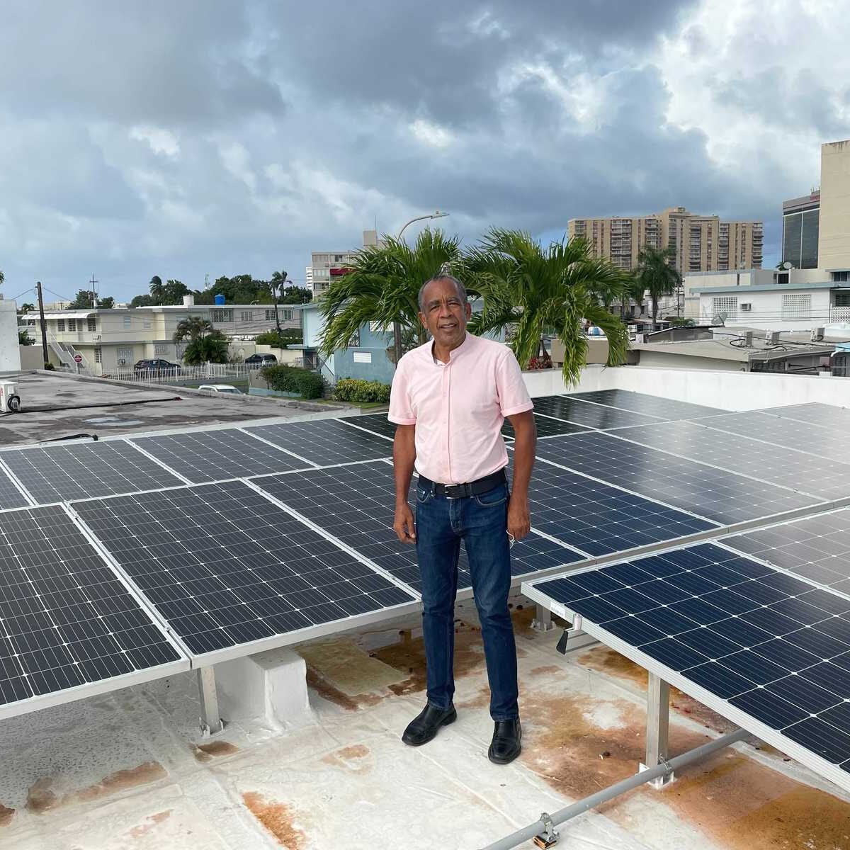 Man standing on roof surrounded by solar panels.