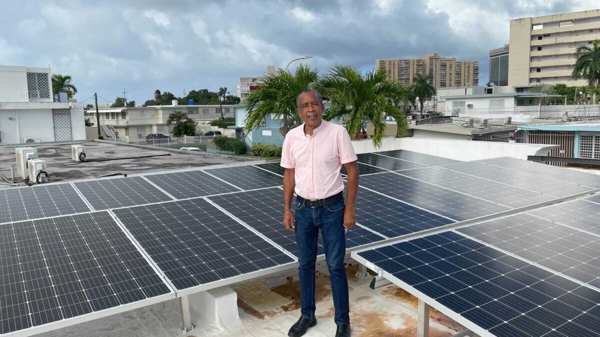 Man standing on roof surrounded by solar panels.