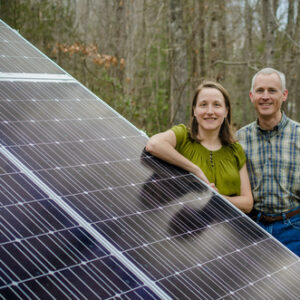 Older couple leaning on solar panel.