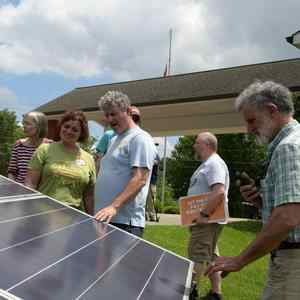 Group of people touching solar panel.