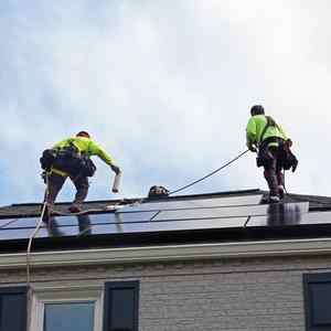 Installers adding solar panels to rooftop.