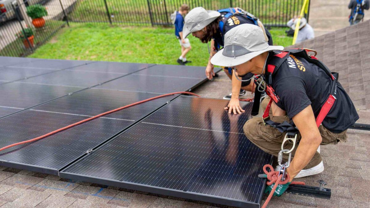 Installers adding solar panels to house rooftop.