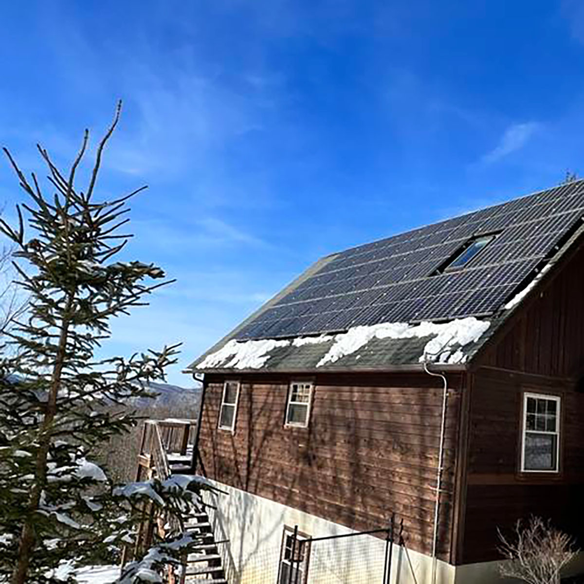 House with solar panel on rooftop with snow.