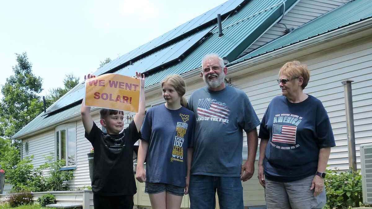 Family of four standing in front of house with rooftop solar panels.