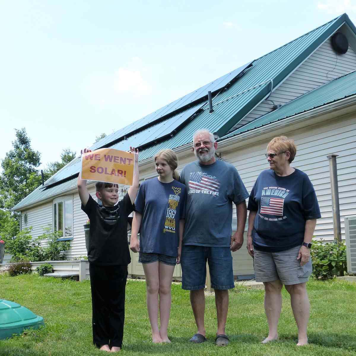 Family of four standing in front of house with rooftop solar panels.