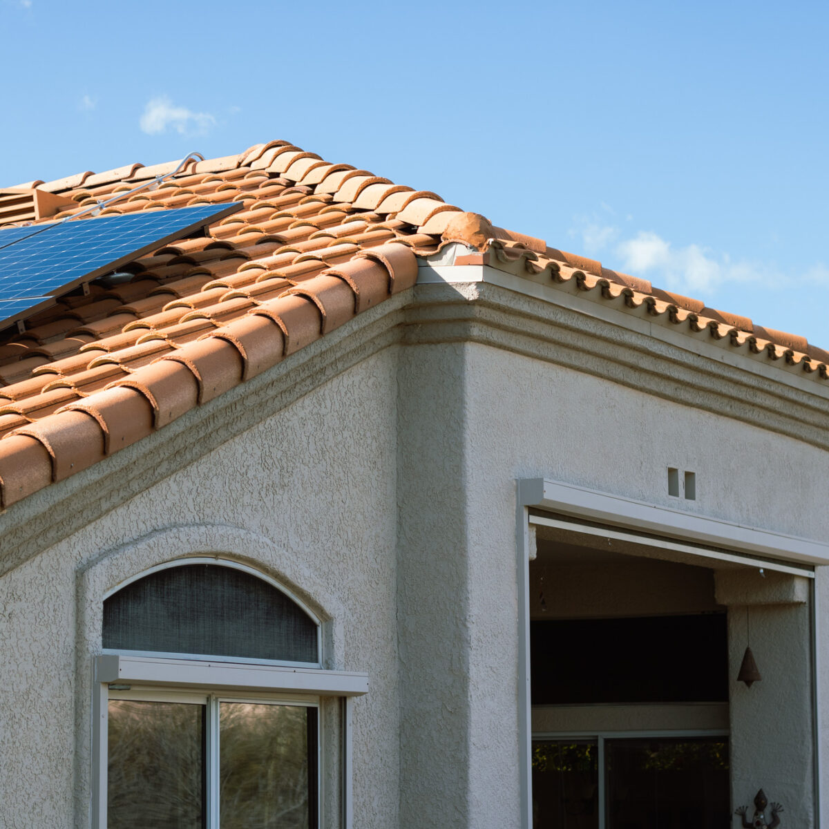 Photo of a clay roof home with solar panels and a cactus in the yard.