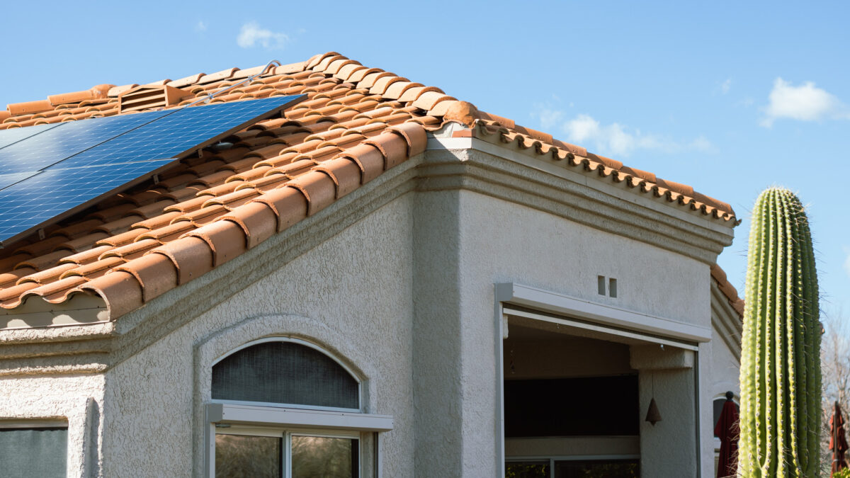 Photo of a clay roof home with solar panels and a cactus in the yard.
