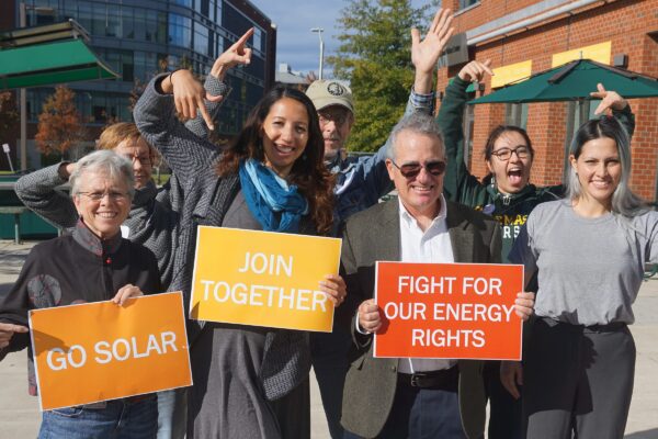 7 people with signs reading go solar, join together and fight for your energy rights