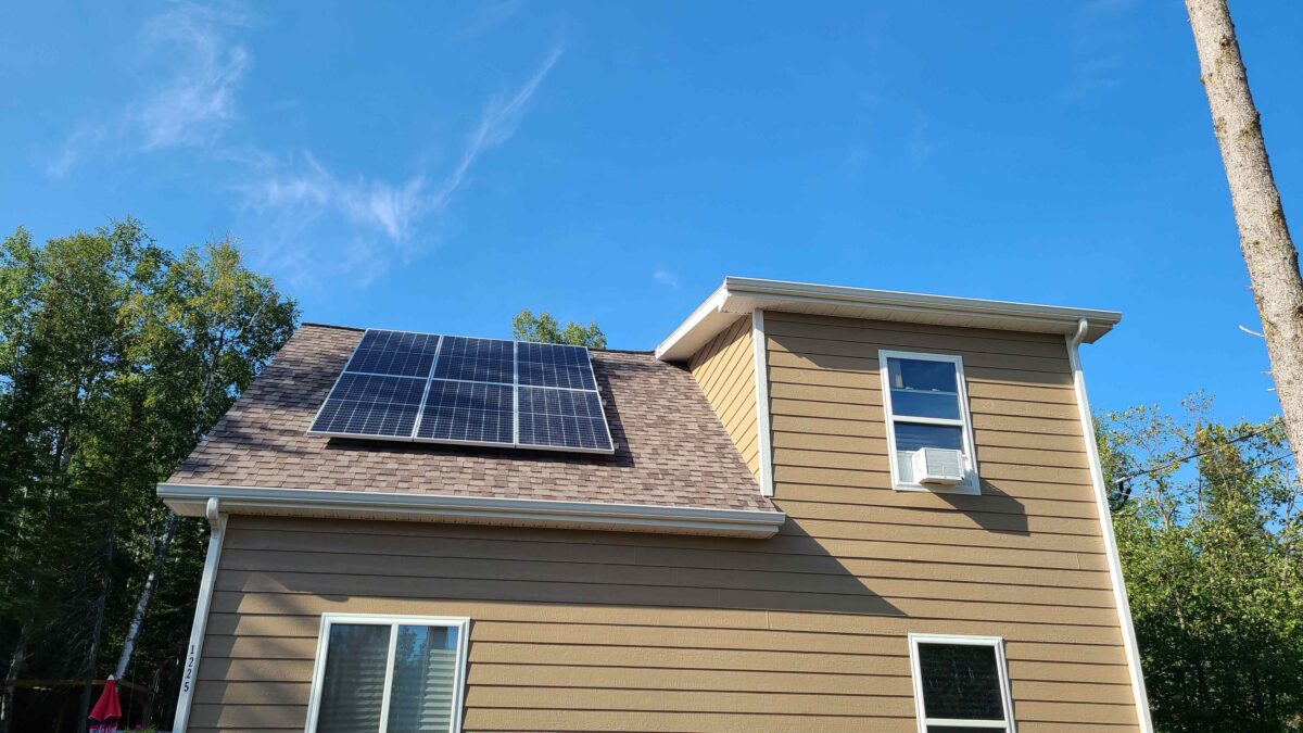 Rooftop solar on a tan home with a bright blue sky above it.