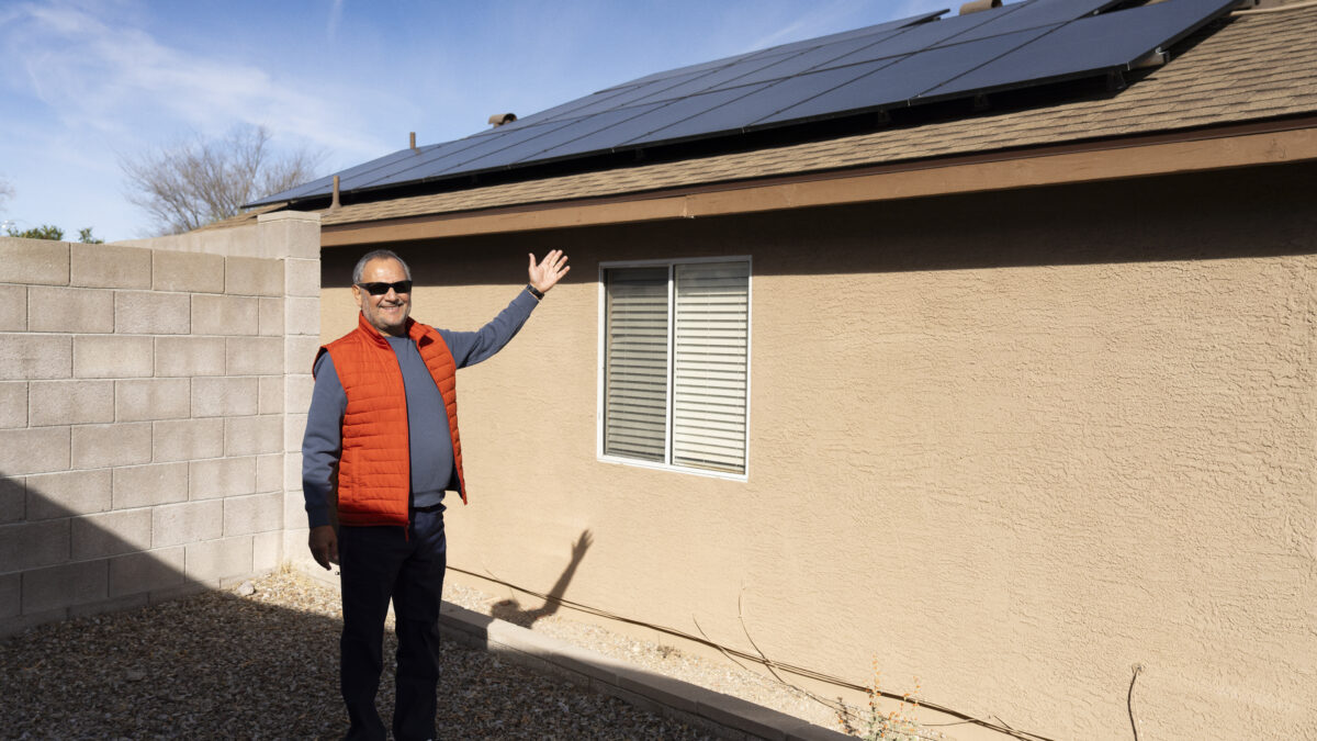 Homeowner gesturing at their rooftop solar array.