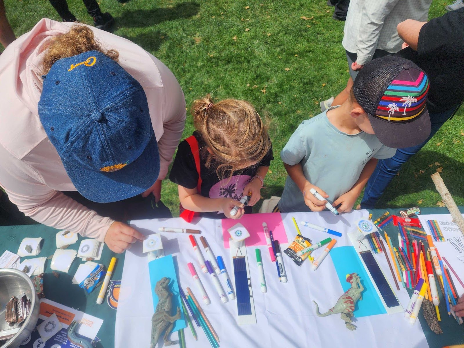 One adult and two children at a craft table.