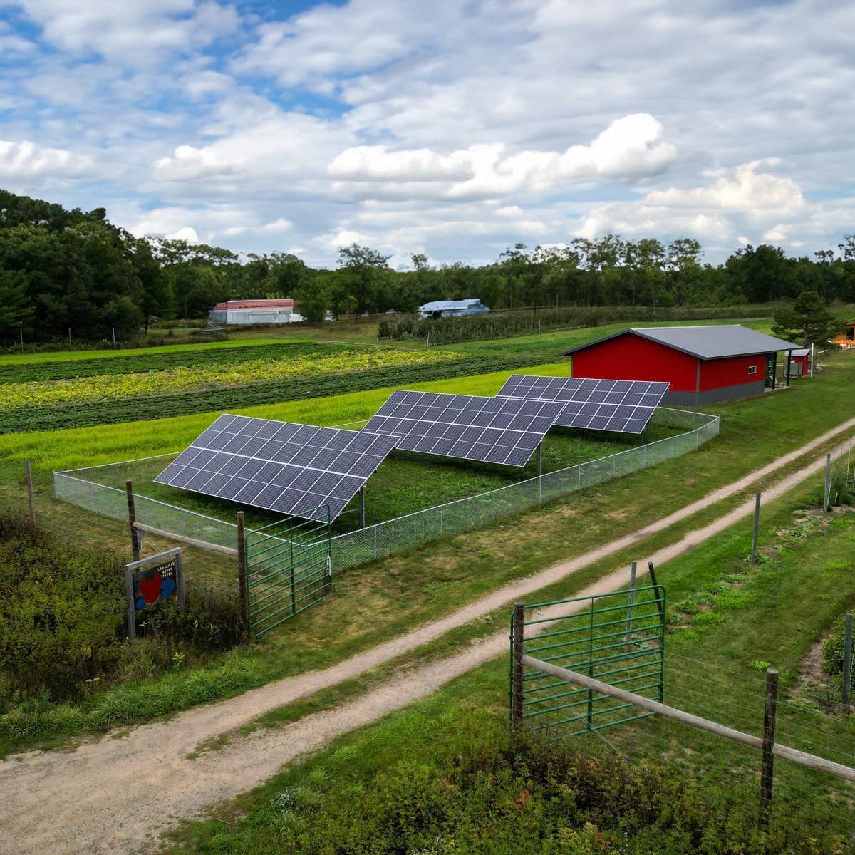 Photo of a ground mount solar array on a farm with a red building