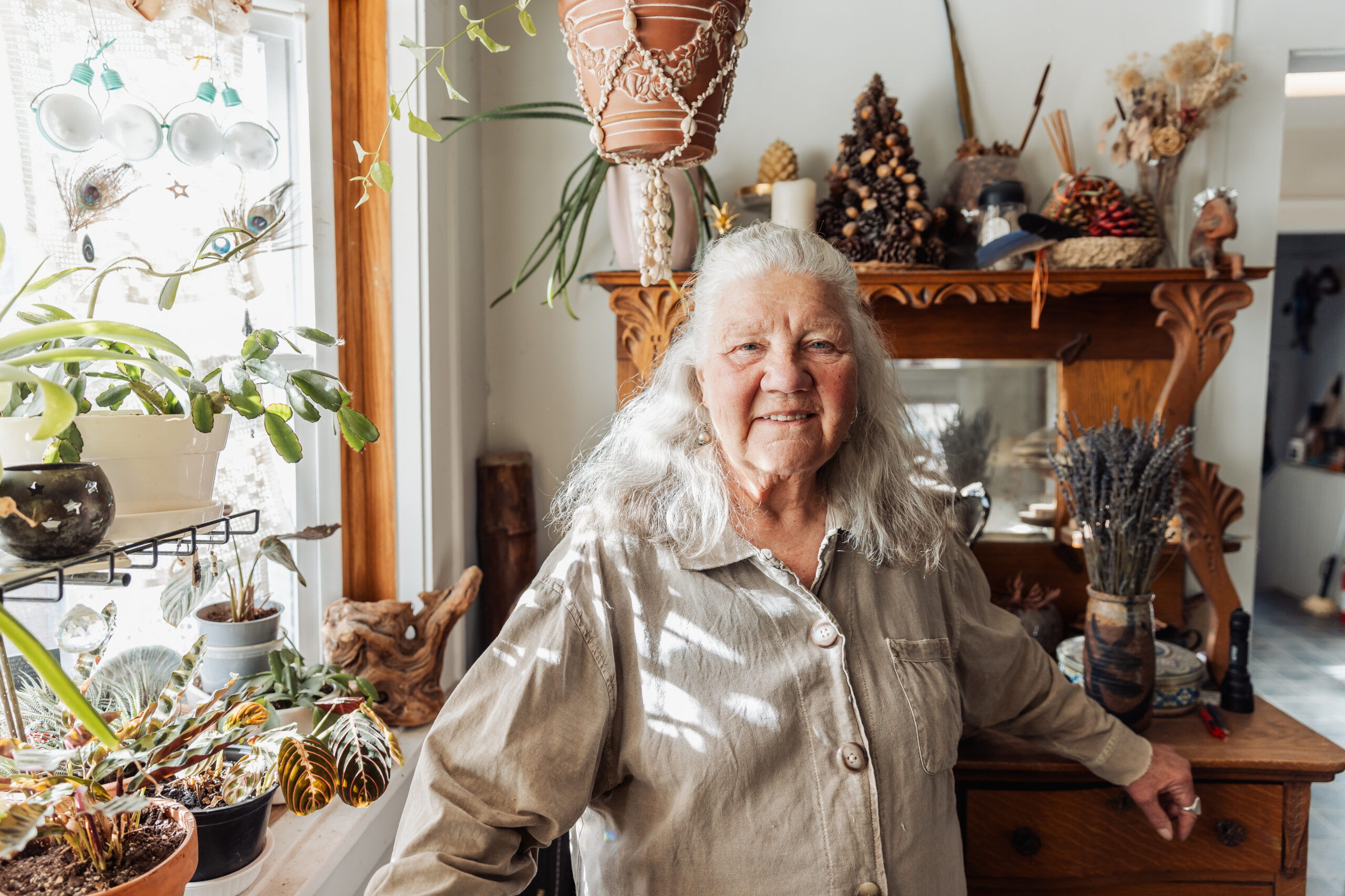 Shawna Crocker poses in her home, surrounded by plants and trinkets 